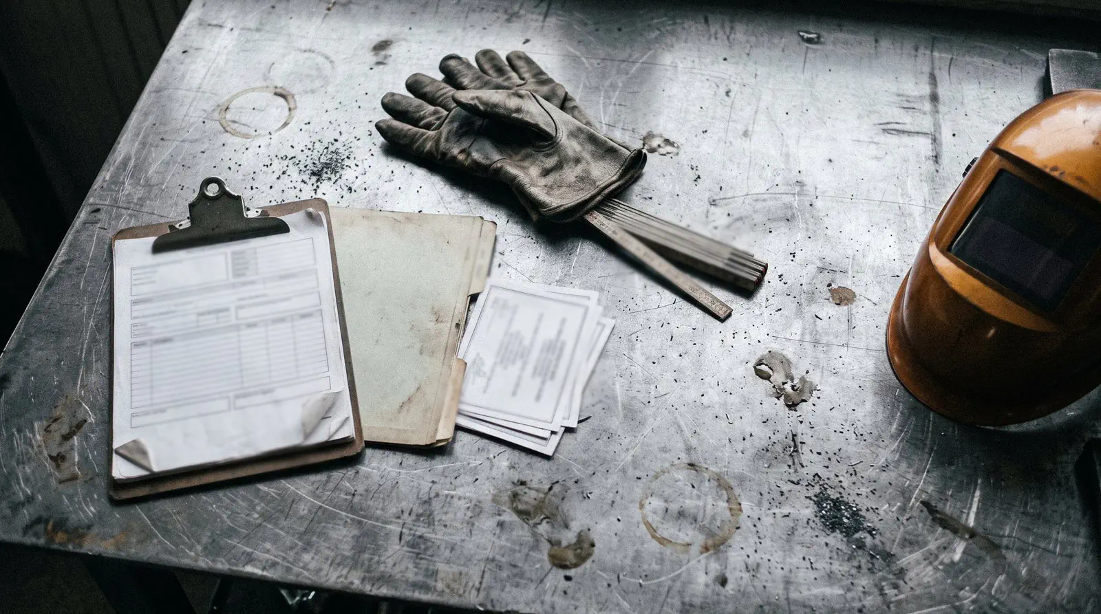 Welder qualification certificates, work forms and welding gloves on a workbench